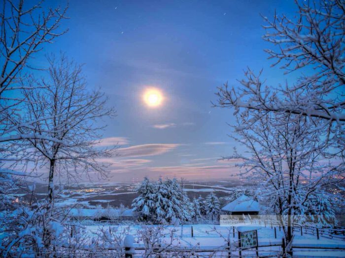 Nachtpanorama des Potzbergs im Winter. Heller Mond leuchtet über der schneebedeuten Landschaft. Aufgenommen im Landkreis Kusel (Westpfalz)